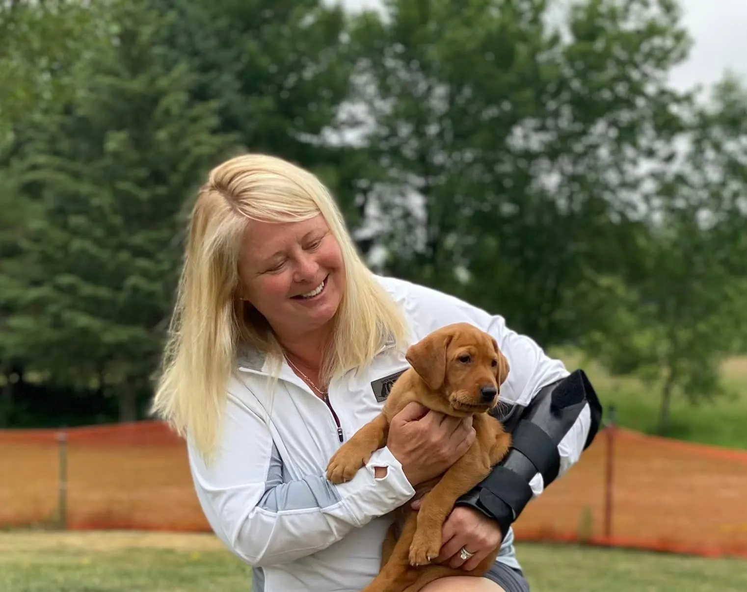 A member of the Quick Trigger Kennels family holding a fox red Labrador puppy
